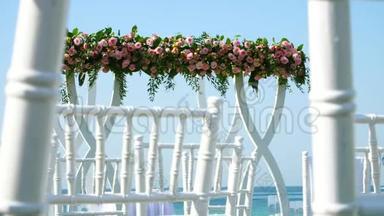 婚礼装饰，用玫瑰装饰的白色婚礼拱门，海滩上的婚礼，婚礼的准备